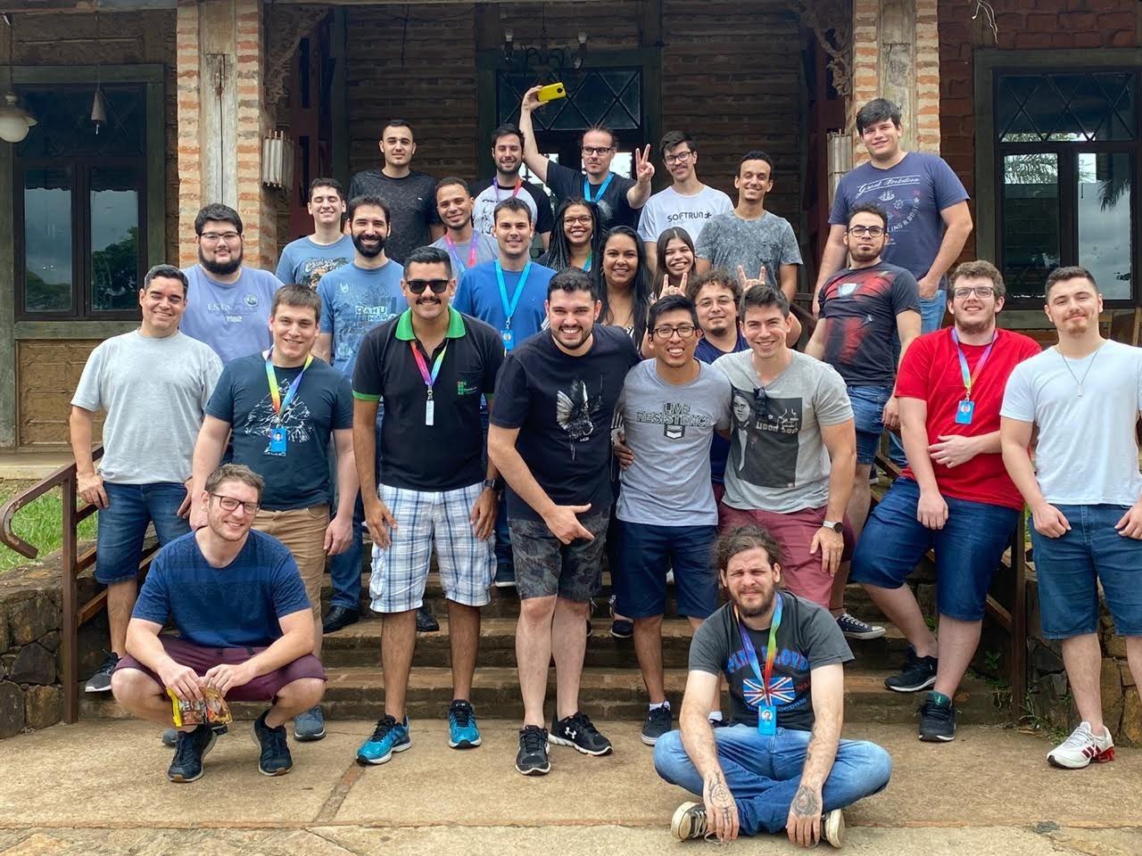 Equipe reunida na escada de um casarão durante encontro informal de time de tecnologia.