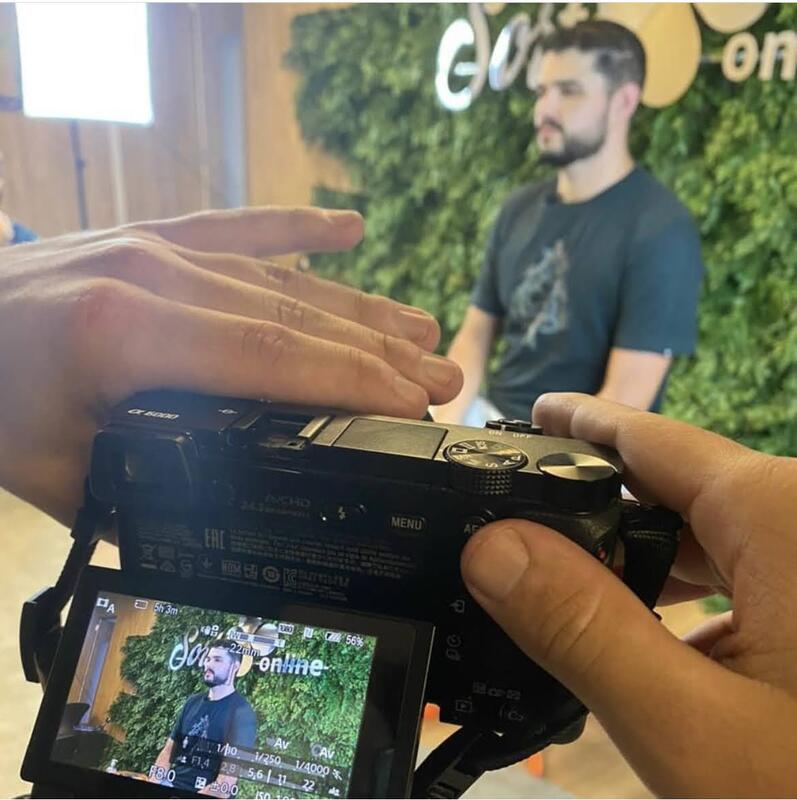 Bastidores de gravação no Sorte Online, com câmera enquadrando Bruno Prates diante do painel de folhagem.